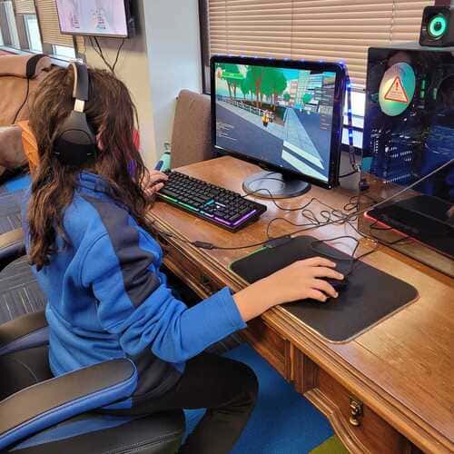 Girl playing a game on a desktop computer wearing headphones