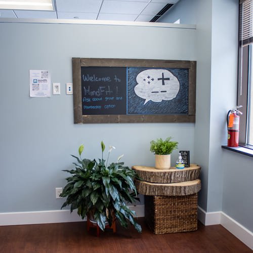 MindFit welcome sign in the main lobby with office plants underneath.